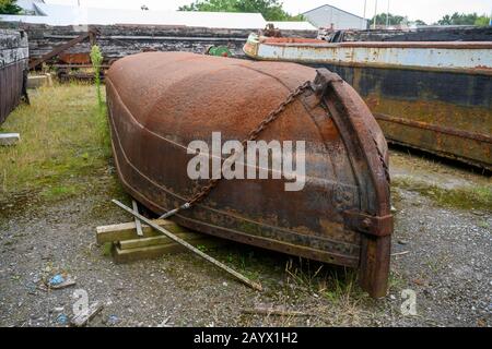 Old iron plate ice breaker, covered in rust, used on the UK's inland waterways now laying upturned in a storage yard. Stock Photo