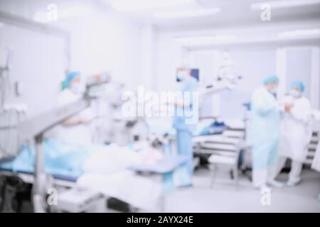 Abstract medical blurred background of operating room, patient lies on table, doctors working Stock Photo