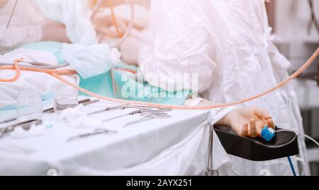 Hand of patient on operating table, doctors are operation person. Light blue background Stock Photo