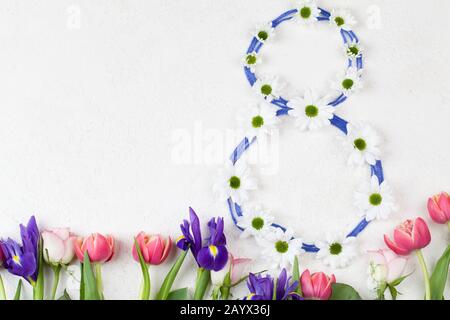 white chrysanthemums stacked in number 8 with red tulips and purple irises on white background. Women's day congratulations. 8 March background copy s Stock Photo