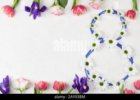 white chrysanthemums stacked in number 8 with red tulips and purple irises on white background. Women's day congratulations. 8 March background copy s Stock Photo