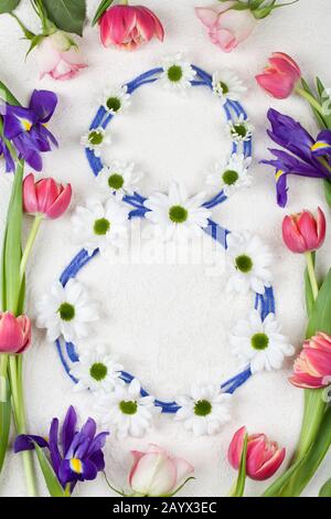 white chrysanthemums stacked in number 8 with red tulips and purple irises on white background. Women's day congratulations. 8 March background Stock Photo