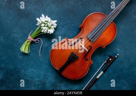 Old Violin and Fresh beautiful bouquet of the first spring forest snowdrops  flowers with red and white cord martisor - traditional symbol of the firs Stock Photo