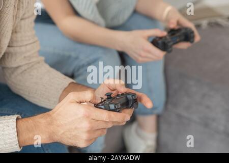 Close-up of unrecognizable people sitting on sofa and playing video game Stock Photo