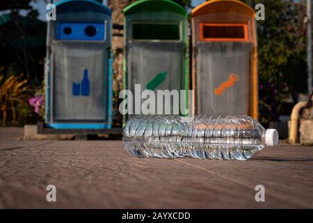 Close up clear plastic bottle water drink with a white cap on ground in the park at bin background, litter on the ground in the garden Stock Photo