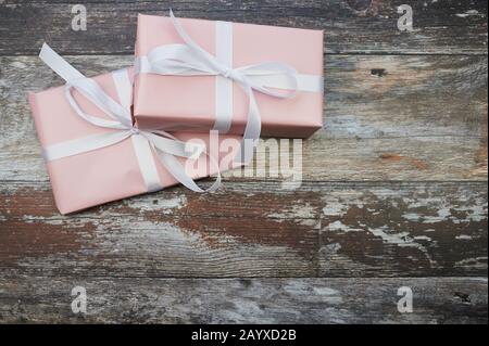 two pink presents in the left corner against brown wooden background with copy space Stock Photo