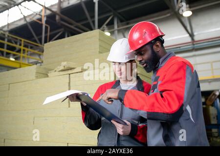 Horizontal medium portrait shot of two professional factory engineers doing paperwork together Stock Photo