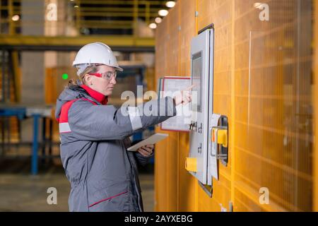 Horizontal medium side view portrait of Caucasian female factory engineer setting up equipment Stock Photo