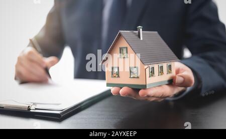 Real estate agent is holding a house model. Buy, loan for a house Stock Photo