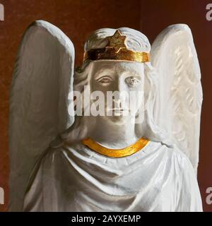 A white painted statue of an angel with golden star, holding a shell with holy water, located at the entrance of Binondo church in Manila, Philippines Stock Photo