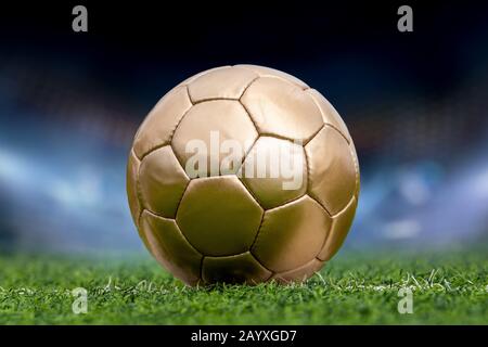 Closeup golden soccer ball and stadium with fans the night Stock Photo