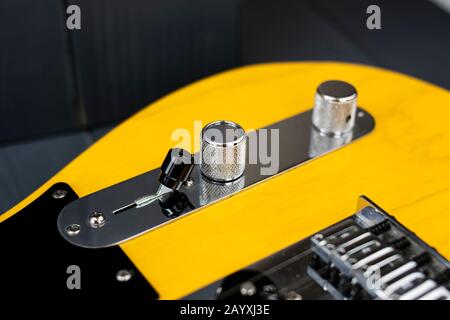 Close-up of the tone and volume controls, and pickup switch of a classic electric guitar in yellow and black colors Stock Photo