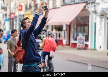 Cambridge, UK, August 1, 2019. Turists walking down and taking pictures at the street of Cambridge on a busy sunny day in front of Kings College Stock Photo