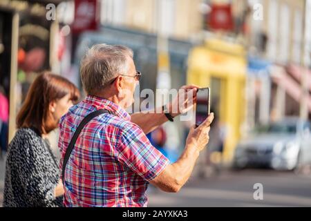 Cambridge, UK, August 1, 2019. Turists walking down and taking pictures at the street of Cambridge on a busy sunny day in front of Kings College Stock Photo