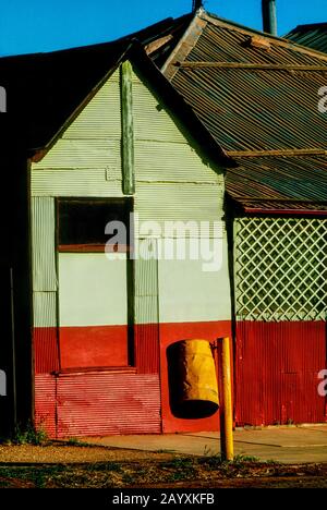 Old house boarded up in outback town, with bright yellow bin in main street Western Australia Stock Photo