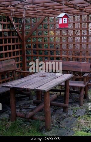 empty garden gazebo with wooden benches and table in early spring Stock Photo