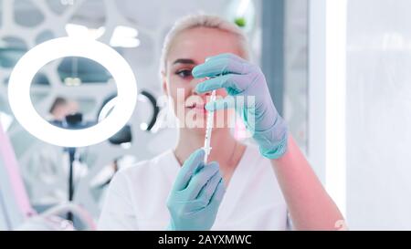 Close-up of female doctor hand with protective rubber gloves holding syringe with vaccine.  Medicine safety and health care concepts. Stock Photo