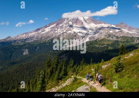 People hiking the Pinnacle Peak trail in Mount Rainier National Park with Mount Rainier in the background, Washington State, USA. Stock Photo