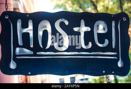 Retro aged blue signboard with inscription hostel in English hanging on chain Stock Photo