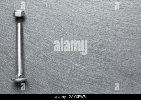 Stainless steel screws on a black texture background Stock Photo