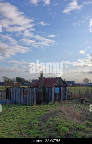 An abandoned and derelict Railway Hut with a Blue keep out Sign beside the main East Coast Rail track between Edinburgh and Aberdeen. Stock Photo