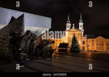 Warsaw, Poland - December 27, 2019: Warsaw Uprising Monument (Polish: Pomnik Powstania Warszawskiego) and Field Cathedral of the Polish Army at night, Stock Photo