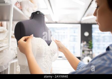 Professional seamstress working on wedding dress corset in bridal workshop, horizontal shot Stock Photo