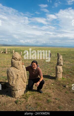 Mongolian man next to Ongot grave (Neolithic grave) in Tuul River valley with carved grave stones, carved by people of Turkic origin about 1200 ? 1400 Stock Photo