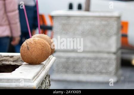 Two coconuts left on marble in the middle of the street. There are colored straws on it. Stock Photo