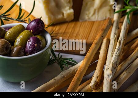 Grissini snack bread sticks and Asiago cheese with olives. Stock Photo