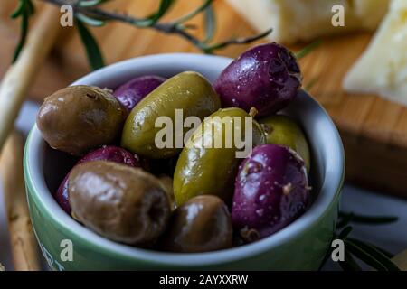 Bowl of olives with Asiago cheese and grissini bread sticks in the background. Stock Photo