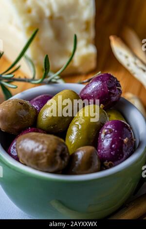 Bowl of olives with Asiago cheese and grissini bread sticks in the background. Stock Photo