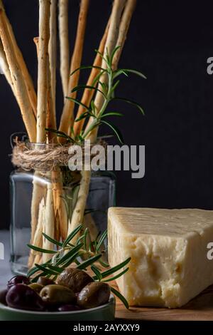 Grissini snack bread sticks and Asiago cheese with olives. Stock Photo
