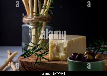 Grissini snack bread sticks and Asiago cheese with olives. Stock Photo