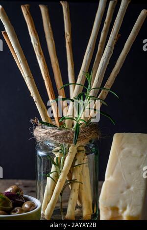 Grissini snack bread sticks and Asiago cheese with olives. Stock Photo