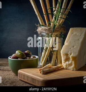 Grissini snack bread sticks and Asiago cheese with olives. Stock Photo