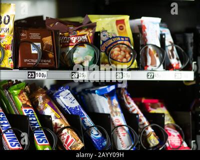 Moscow, Russia - February 8, 2020: Chocolate bars Snickers, Twix, Milky Way, snacks, cookies and nuts in a transparent glass window of a vending machi Stock Photo