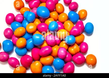 Pile of many multi-colored pea candies of blue, red and orange colors isolated on a white background. Sweet background. Close-up. Stock Photo