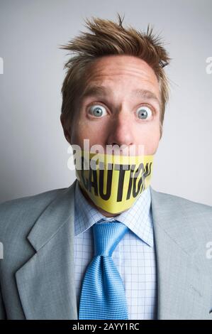 Shocked businessman gagged with yellow caution tape Stock Photo - Alamy