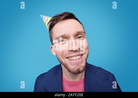 Shocked young bearded man in cardigan using modern laptop against blue background Stock Photo