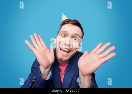 Portrait of expressive young man screaming into loudspeaker against blue background Stock Photo