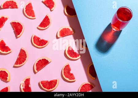 Glass of grapefruit lemonade on a blue background and grapefruits slices on pink background. Above view of summer cocktail. Healthy eating. Flat lay. Stock Photo