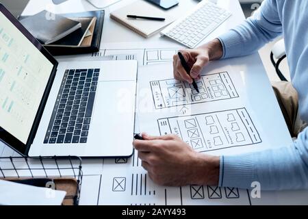 Horizontal high angle shot of unrecognizable application developer working on new software drawig scheme on paper Stock Photo