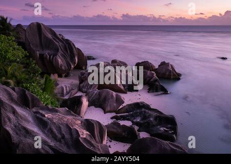 Twilight on rocks and ocean at Source D Argent beach on La Digue, Seychelles Stock Photo