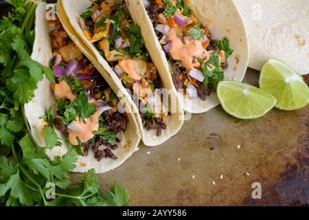 Korean Beef Tacos: Korean-Mexican fusion cuisine - Tacos made with ground beef and topped with cilantro, kimchi, and sriracha mayonnaise Stock Photo