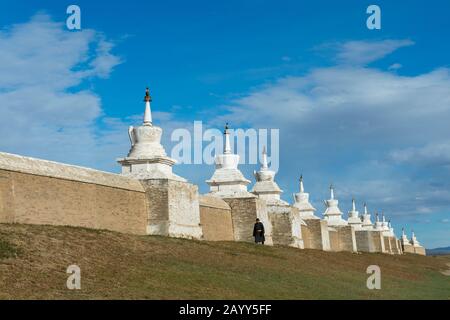 A Mongolian man is walking along the wall with stupas which is surrounding the Erdene Zuu monastery in Kharakhorum (Karakorum), Mongolia. Stock Photo