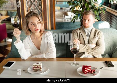Horizontal shot of resentful woman telling something to man she experiencing conflict with while having date Stock Photo