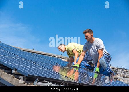 Installing solar photovoltaic panel system. Solar panel technician installing solar panels on roof. Alternative energy ecological concept. Stock Photo