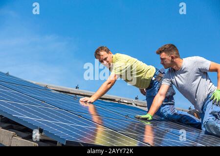 Installing solar photovoltaic panel system. Solar panel technician installing solar panels on roof. Alternative energy ecological concept. Stock Photo