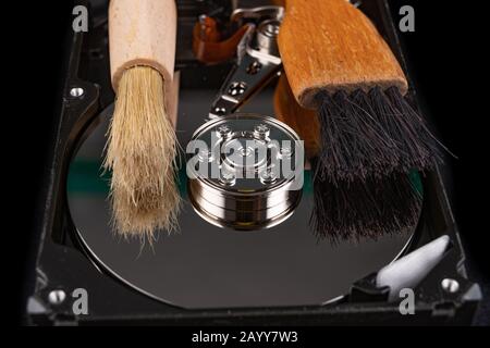 Cleaning the hard disk with a brush. Vacuuming old disk data on your computer. Dark background. Stock Photo